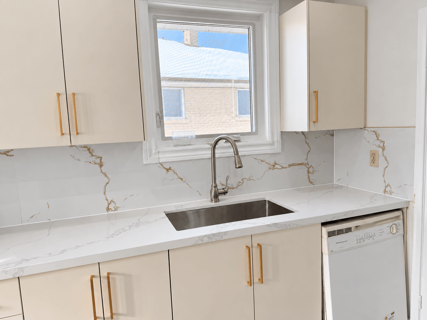 White kitchen cabinets with brass handles and a tiled backsplash