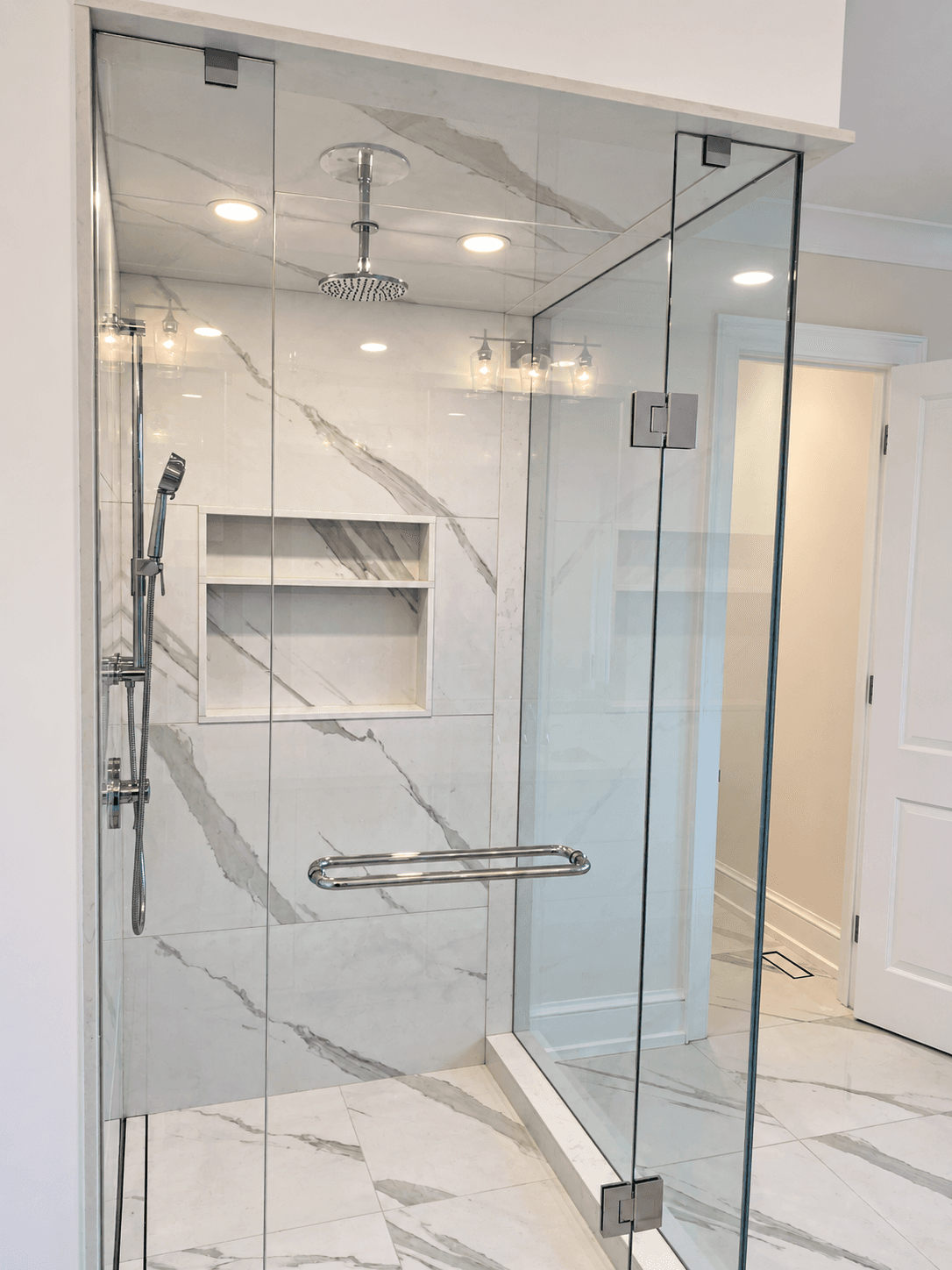 Glass shower with chrome hardware and marble-style wall tile